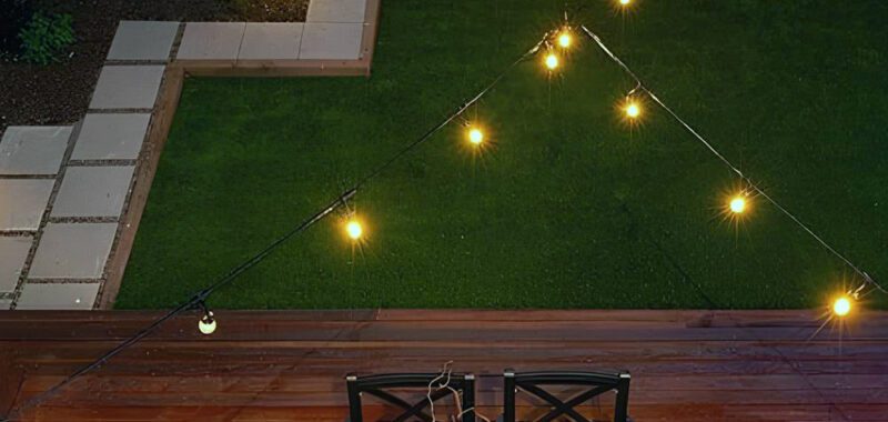 Chic Backyard Design With Dark Dining Set, Firepit, And String Lights